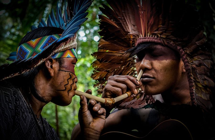 An image of two indigenous people using shamanic snuff.